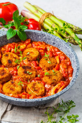 Vegetarian vegetable meatballs with tomato sauce in frying pan.