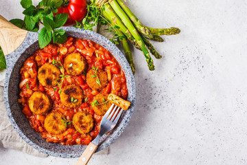 Vegetarian vegetable meatballs with tomato sauce in frying pan.