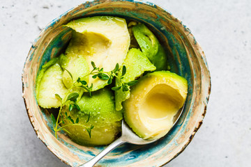 Peeled avocado halves in a bowl, top view. Cooking guacamole.
