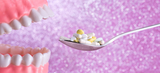 Open mouth, teeth and spoon full of pills – taking vitamins or overdose