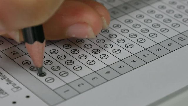 Student hand filling out in answer sheet with standardized test form