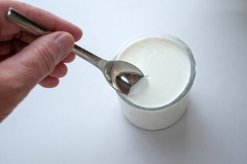 A hand holding/scooping yogurt from a glass.