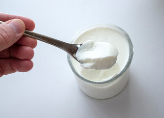 A hand holding/scooping yogurt from a glass.