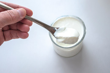 A hand holding/scooping yogurt from a glass.