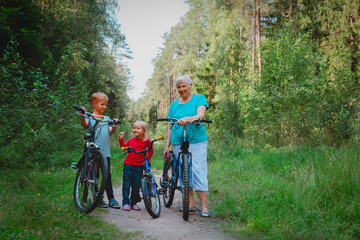 Obraz premium active senior grandmother with kids riding bikes in nature
