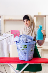 Woman in hijab doing clothing ironing at home