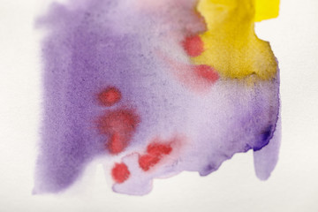 close up view of bright yellow, purple and red watercolor paint spills