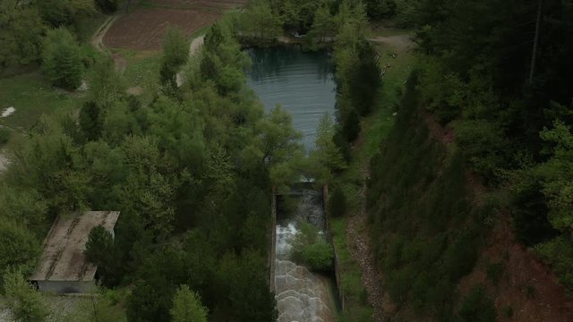 Water flowing in pond hidden in pine trees at Lake Doxa, Greece. Aerial Establishing Shot