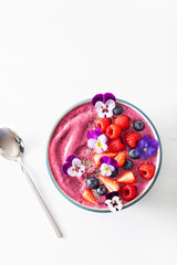 healthy summer berry smoothie bowl with flowers and chia seed