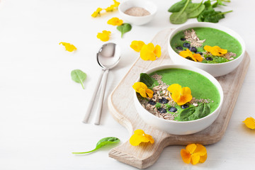 green spinach smoothie bowl with blueberry, chia seed and edible pansy flowers