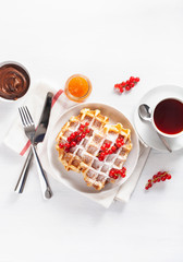 breakfast waffle with berry, jam, chocolate spread and tea. Top view