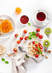 healthy breakfast with oatmeal porridge, strawberry, nuts, toast, jam and tea. Top view