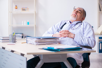 Old male doctor working in the clinic 