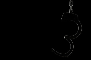 Rimlit open handcuffs on a black background with copy space