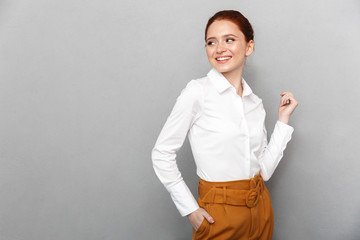 Portrait of happy redhead businesswoman 20s in formal wear smiling at camera and posing in office