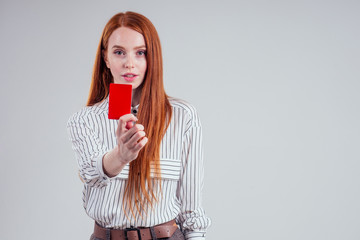 attractive redhead caucasian businesswoman wearing striped shirt holding credit card stop red card removal violation referee sport judge studio white background black friday sale