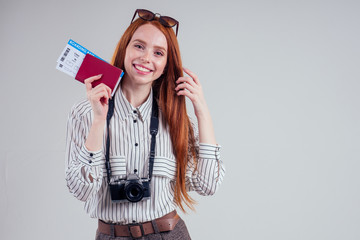redhead happy businesswoman tourist photographer wearing sunglasses white background studio holding passport with tickets visa and camera.