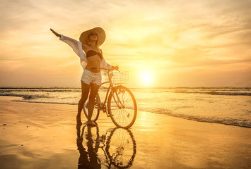 Obraz na płótnie Canvas Happiness woman traveler with her bicycle walking on sea coastli
