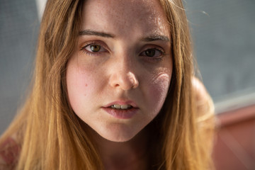 Portrait of young woman in casual summer dress through glass of balcony