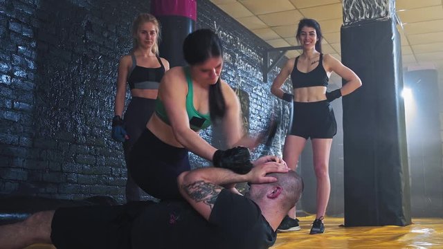 Self defense or kickboxing class. A group of young women in the classroom in the gym for women's self-defense. Strong girl training her punching on the coach