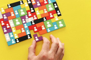 image of tangram puzzle blocks with people icons over wooden table ,human resources and management concept