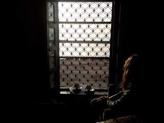 woman having coffee next to window