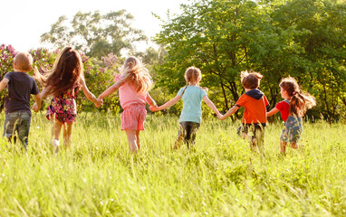 a group of children playing and running in the park on a green gozon.