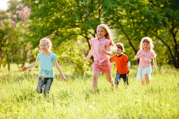 Fototapeta premium a group of children playing and running in the park on a green gozon.