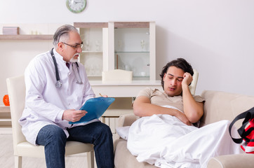 Old male doctor visiting young male patient  