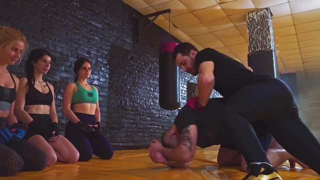 Self defense or kickboxing class. A group of young women in the classroom in the gym for women's self-defense. Two trainers showing acceptance of protection