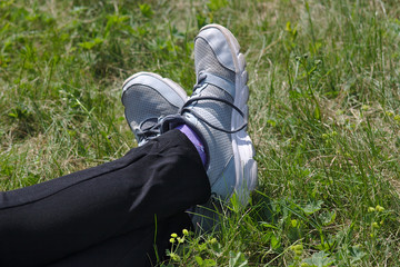 feet in gray sneakers on the grass
