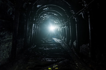 Dark abandoned coal mine with rusty lining in backlight - obrazy, fototapety, plakaty