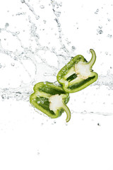 Naklejka premium fresh green bell pepper halves and water splash with drops isolated on white