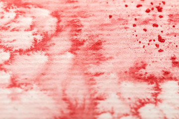close up view of red colorful watercolor paint spill on textured paper background