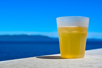 a glass of beer infront of  blue sky and sea