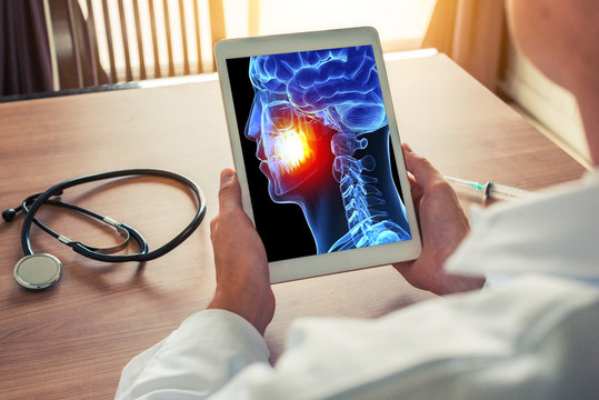 Doctor or dentist holding a digital tablet with x-ray of 3D skull. Pain on the teeth. Headache migraine or trauma concept.