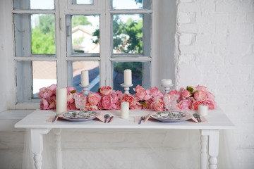 bouquet of pink orchids, roses and peons decorates the dining table near the window
