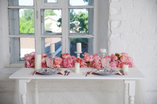 bouquet of pink orchids, roses and peons decorates the dining table near the window