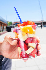 young man eating a fruit salad outdoors