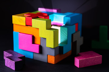 Cube made of multicolored wooden geometric shapes.
