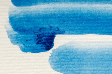 blue watercolor paint brushstrokes on white textured background