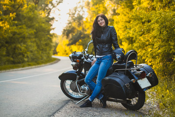 Plakat attractive brunette motorcyclist sits on a motorcycle. adventure concept
