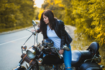 attractive brunette motorcyclist sits on a motorcycle. adventure concept