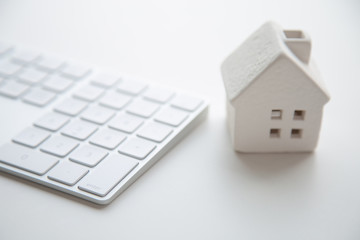 A white ceramic house on computer keyboard.