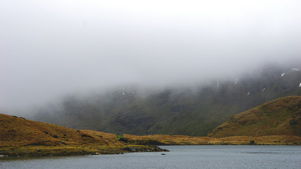 Stunning landscape with foggy and moody skies among the mountains and lake – captured during a hike at Snowdon in winter (Snowdonia National Park, Wales, United Kingdom)