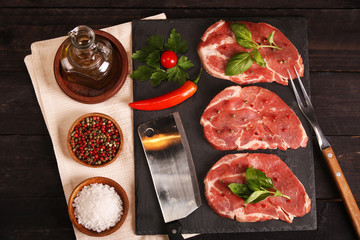 Raw pork meat steak with vegetables, salt, rosemary and spices cooking over stone table. Top view.