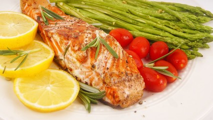 Grilled rosemary salmon served with asparagus, lemon, cherry tomatoes