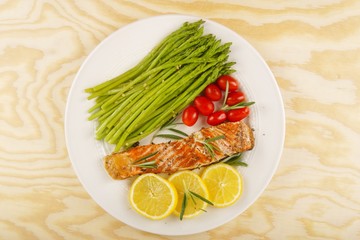 Grilled rosemary salmon served with asparagus, lemon, cherry tomatoes