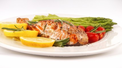 Grilled rosemary salmon served with asparagus, lemon, cherry tomatoes