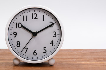 White alarm clock on a wooden table isolated in white background